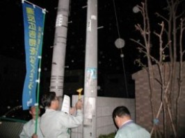 写真:電柱に貼られた違反広告物(はり紙)の撤去作業