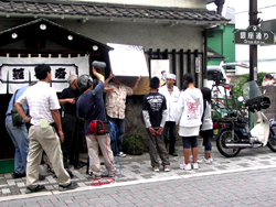 写真：お店の前で野島さんに取材交渉